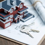 villa house model, key and drawing on retro desktop (real estate sale concept)